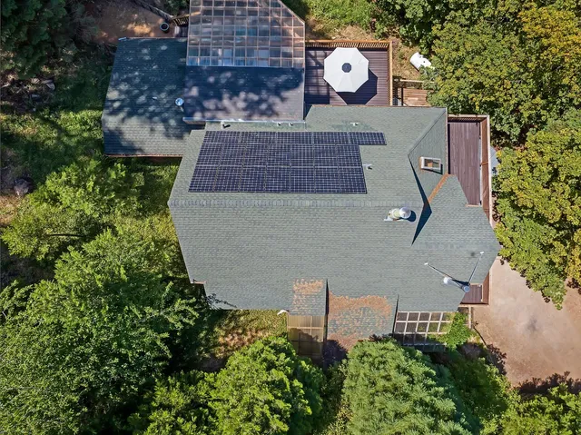 an aerial view of a house with outdoor space and trees all around
