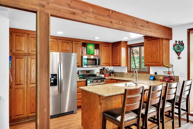 a dining hall with stainless steel appliances granite countertop a refrigerator and a stove top oven