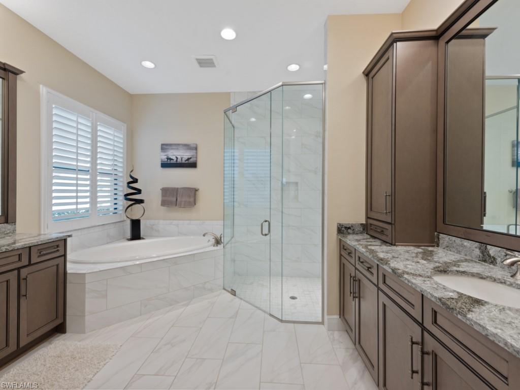 12766 Dundee Lane Naples, FL 34120 - Photo 15 of 37 a spacious bathroom with a granite countertop sink a mirror a bathtub and shower