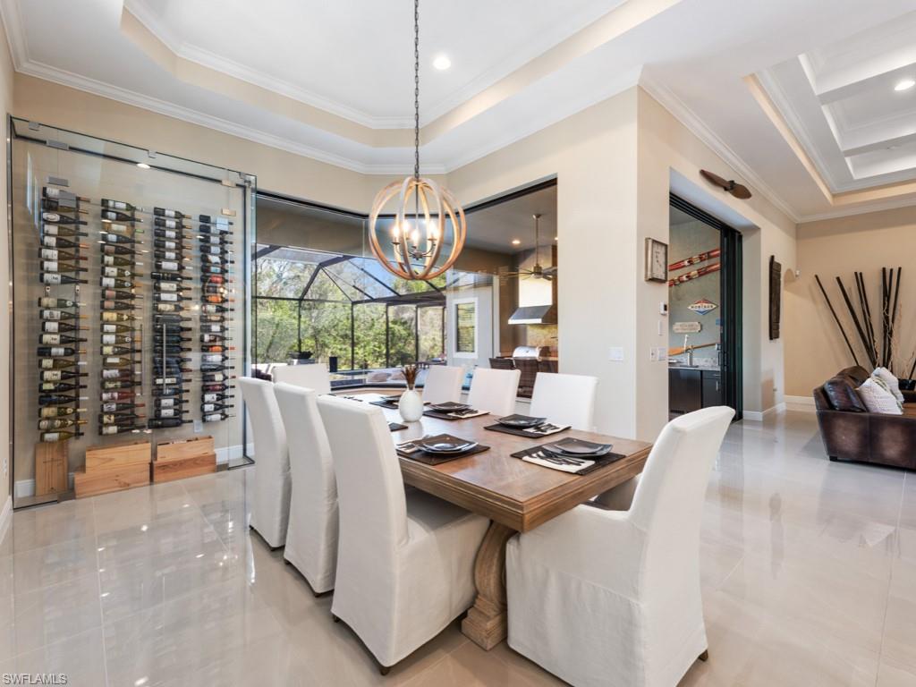 12766 Dundee Lane Naples, FL 34120 - Photo 2 of 37 a dining room with wooden floor a chandelier a glass table and chairs