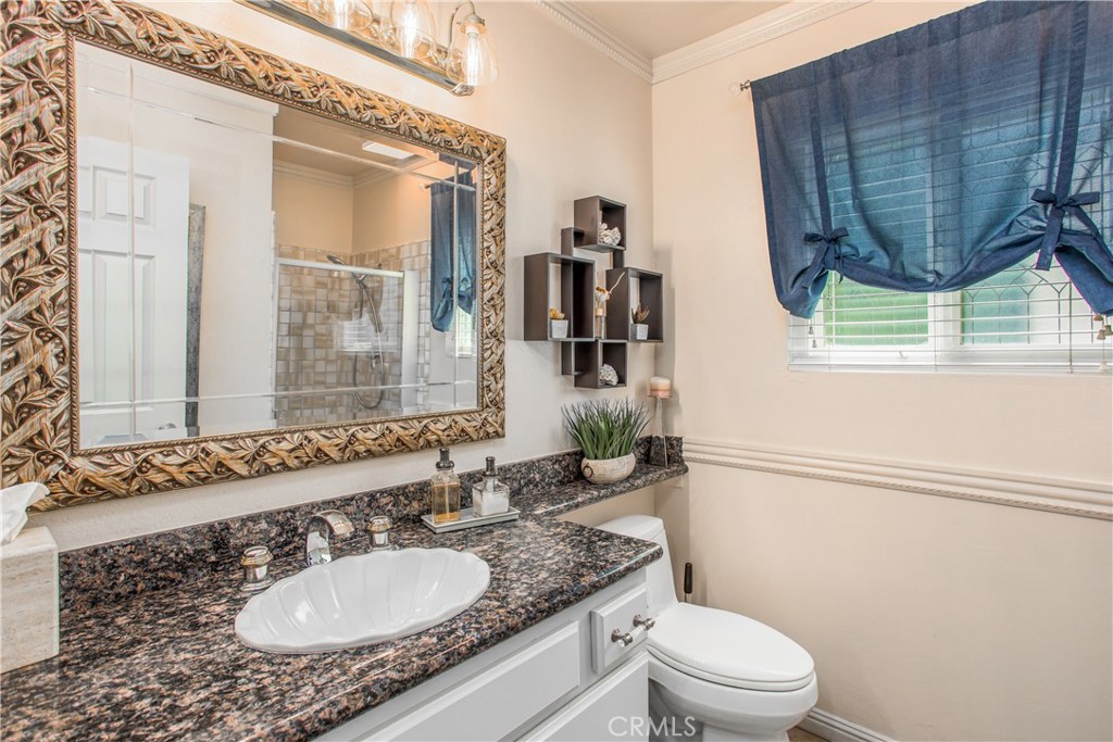 16455 Lake Knoll Parkway Riverside, CA 92503 - Photo 36 of 59 a bathroom with a granite countertop toilet a sink and a mirror