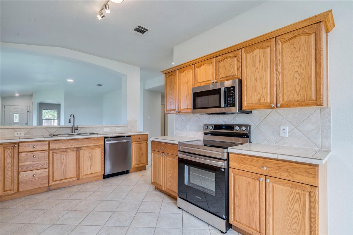 100 Easy Street Hutto, TX 78634 - Photo 7 of 36 A well-equipped kitchen features tile countertops, a brand new stainless steel range and microwave, and abundant cabinetry.