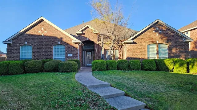 a view of a brick house with a big yard and large trees