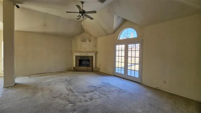 an empty room with windows and fireplace