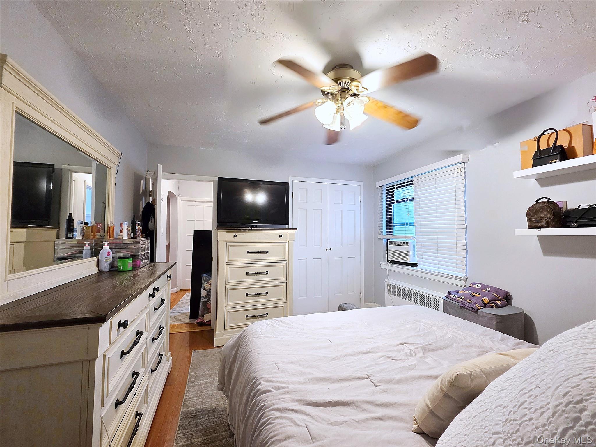 219-12 75th Avenue, Unit LOWR Queens, NY 11364 - Photo 16 of 22 a bedroom with a bed and a flat tv screen on dresser