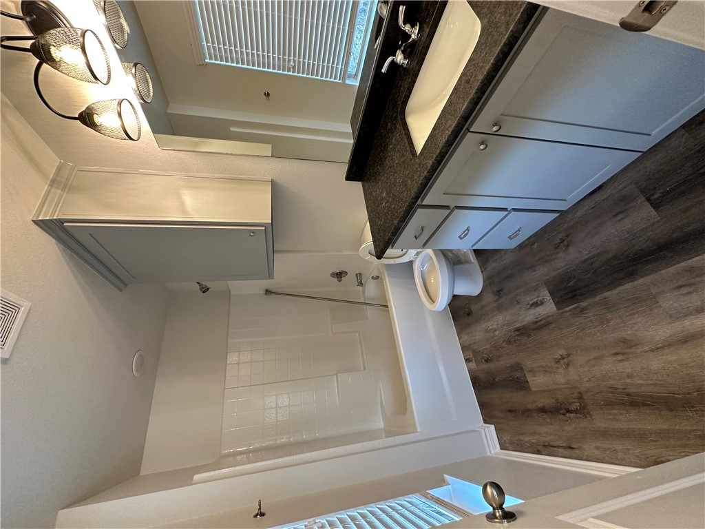 11144-11142 Stillwater Road College Station, TX 77845 - Photo 15 of 22 Bathroom with washtub / shower combination, vanity, and dark wood-type flooring
