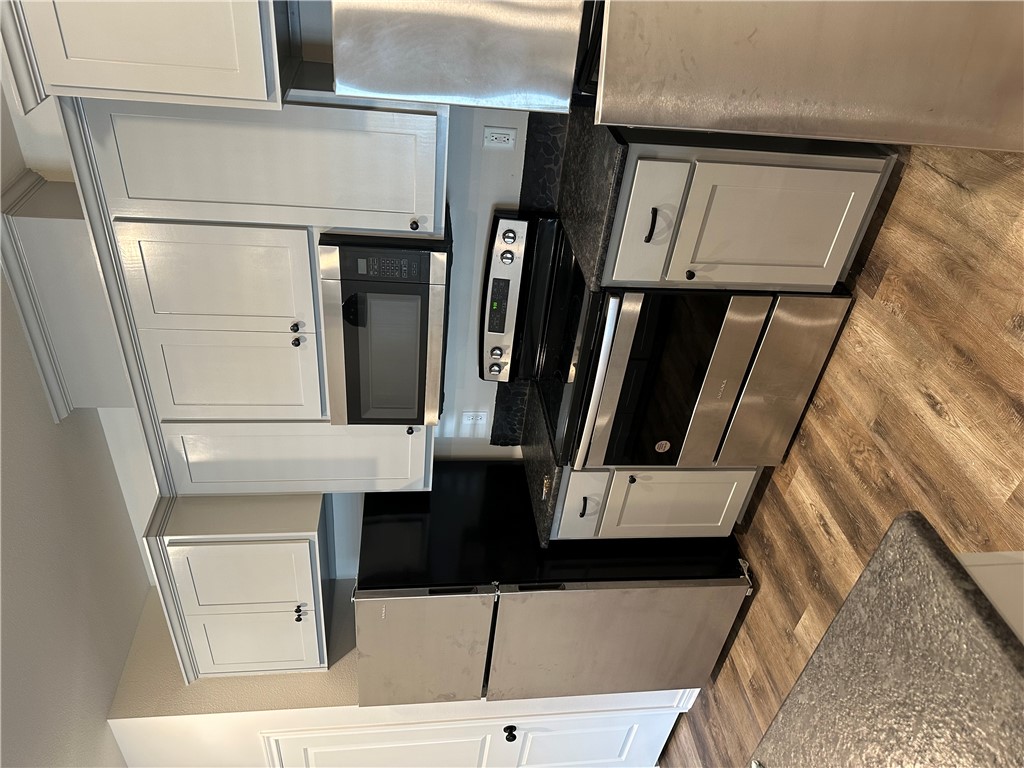 11144-11142 Stillwater Road College Station, TX 77845 - Photo 4 of 22 Kitchen with appliances with stainless steel finishes, dark wood finished floors, white cabinets, and dark stone countertops