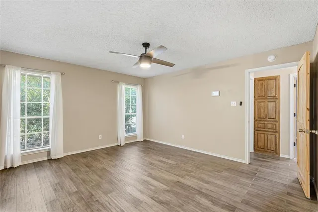 a view of an empty room with window and wooden floor