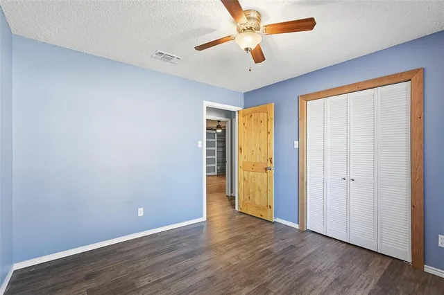 an empty room with wooden floor and ceiling fan