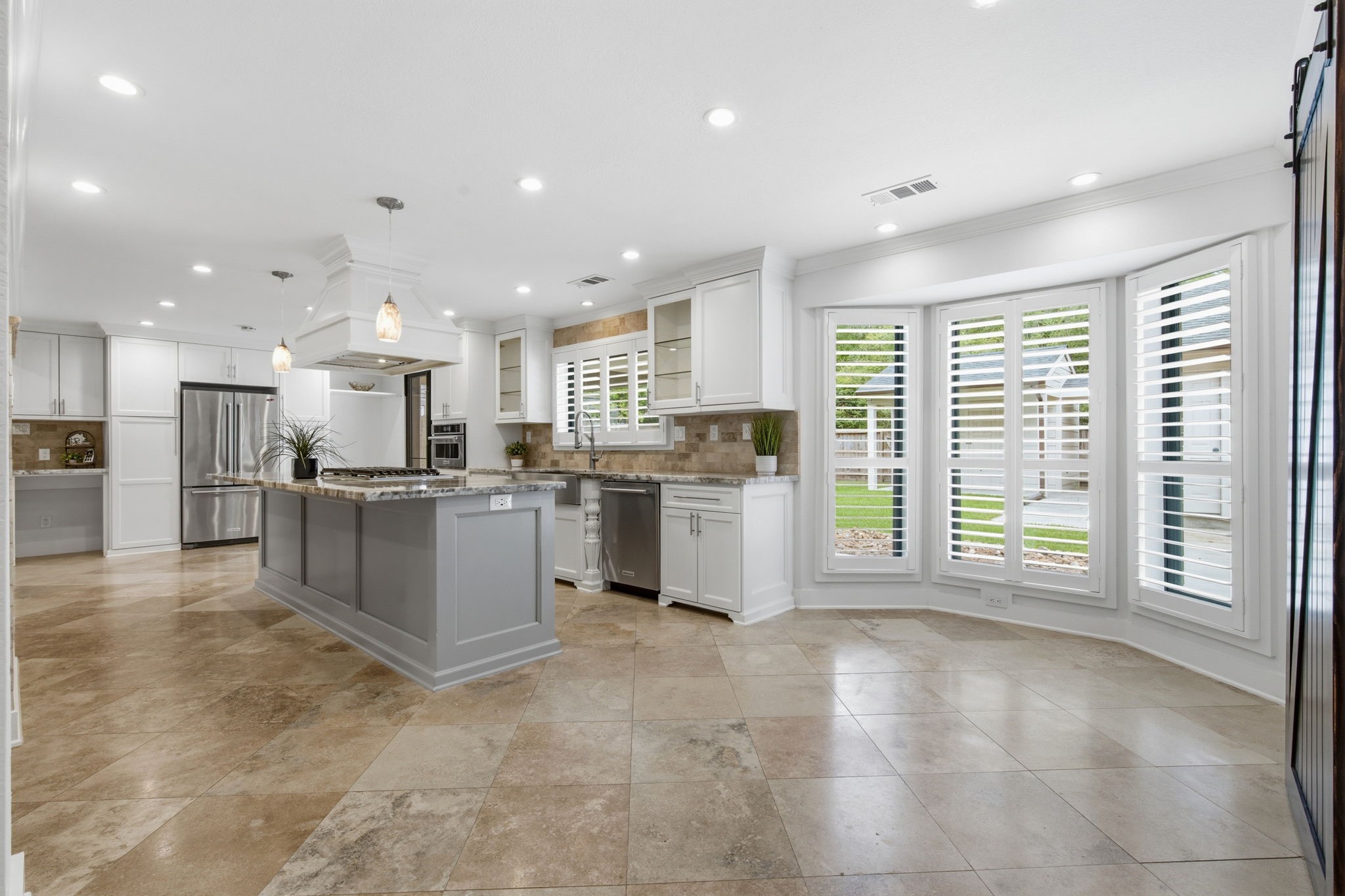 14 Ridgeline Court Spring, TX 77381 - Photo 12 of 40 This spacious kitchen features modern stainless steel appliances, a large central island with pendant lighting, and elegant tile flooring. Ample natural light floods through the bay windows with plantation shutters, creating a bright and inviting atmosphere.