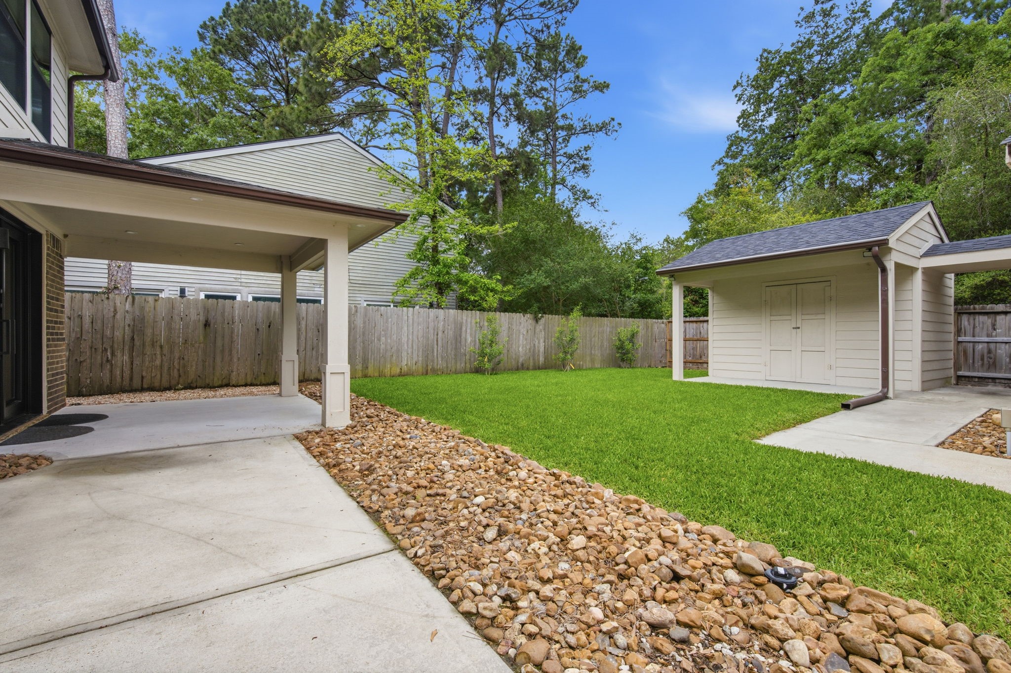 14 Ridgeline Court Spring, TX 77381 - Photo 31 of 40 Beautiful back yard, extended patio with updated gutters, added drain/leach line, storage building on slab with shingled roof, gutters and attached walkway to the detached garage with side door entry.