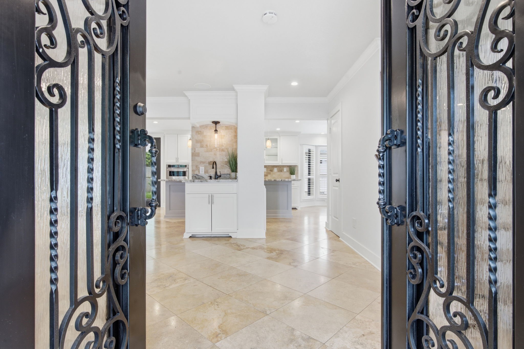 14 Ridgeline Court Spring, TX 77381 - Photo 4 of 40 This inviting entryway features elegant wrought iron doors leading to a bright, open-concept family room & kitchen with modern cabinetry, crown molding and travertine tile flooring.