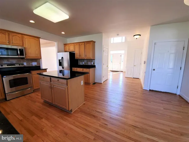 a kitchen with stainless steel appliances a stove top oven a sink cabinets and a wooden floor