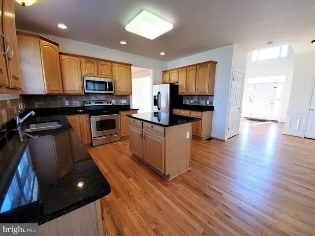 a kitchen with stainless steel appliances granite countertop wooden cabinets a stove top oven a sink and dishwasher