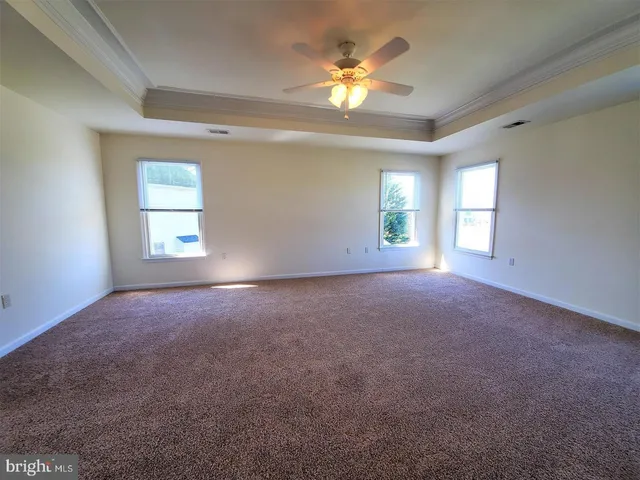 an empty room with windows and ceiling fan