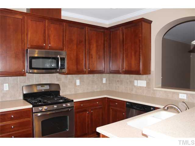 9222 Wooden Road Raleigh, NC 27617 - Photo 6 of 18 Kitchen has hardwood floors, Tall stained wood finish cabinets and tiled backsplash. Stainless Steel appliances including built-in microwave, dishwasher, gas stove with griddle & warming oven, and side-by-side refrigerator.