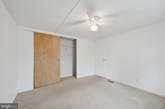 an empty room with a chandelier fan and closet area