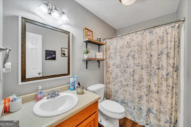 a bathroom with a granite countertop sink a toilet and a mirror
