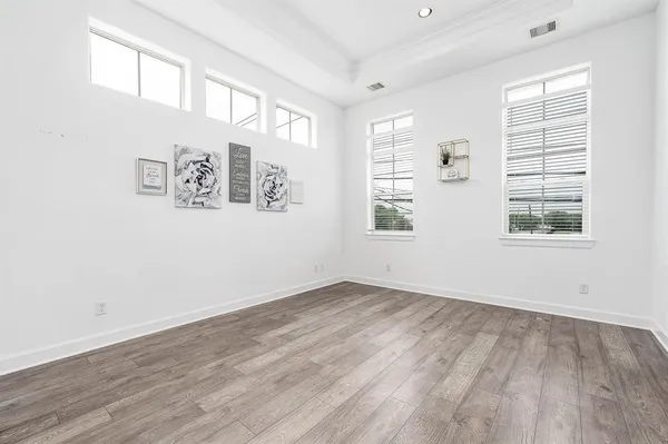 an empty room with wooden floor and windows