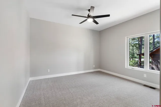an empty room with a ceiling fan and windows
