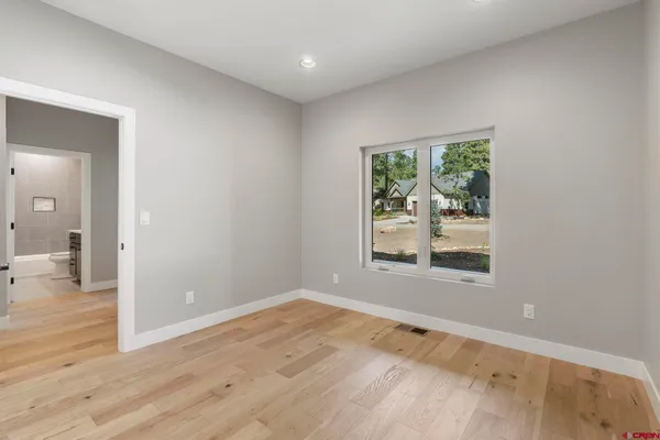 a view of an empty room with wooden floor and cabinets