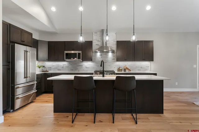 a kitchen with stainless steel appliances granite countertop a refrigerator a stove a sink and a microwave