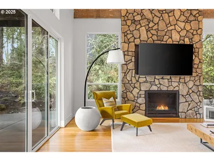 a living room with a fireplace a flat screen tv and a floor to ceiling window