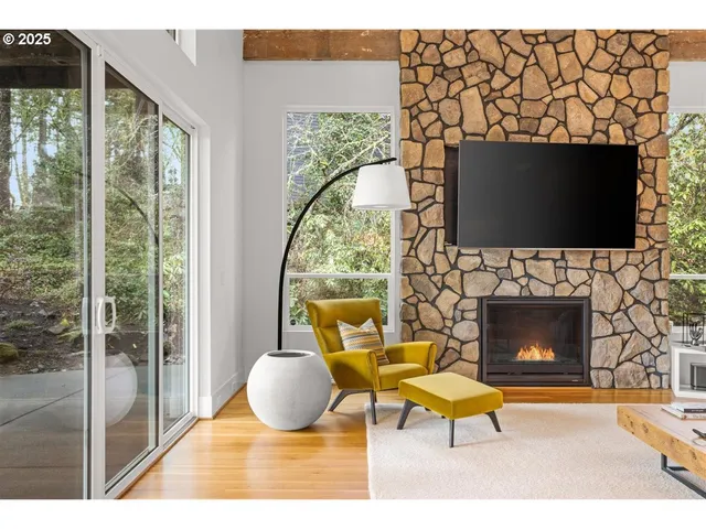 a living room with a fireplace a flat screen tv and a floor to ceiling window