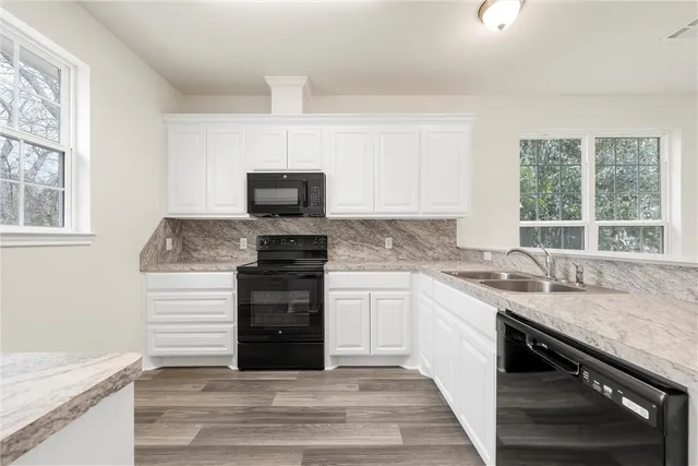 a kitchen with granite countertop cabinets appliances and a window