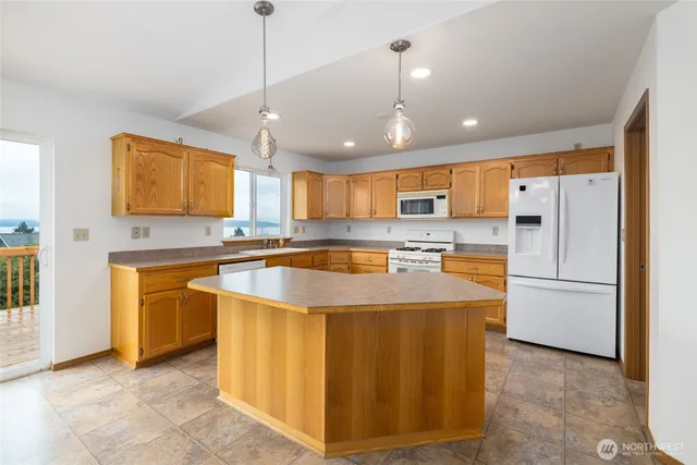 a kitchen with stainless steel appliances granite countertop a refrigerator a sink dishwasher a stove with white cabinets