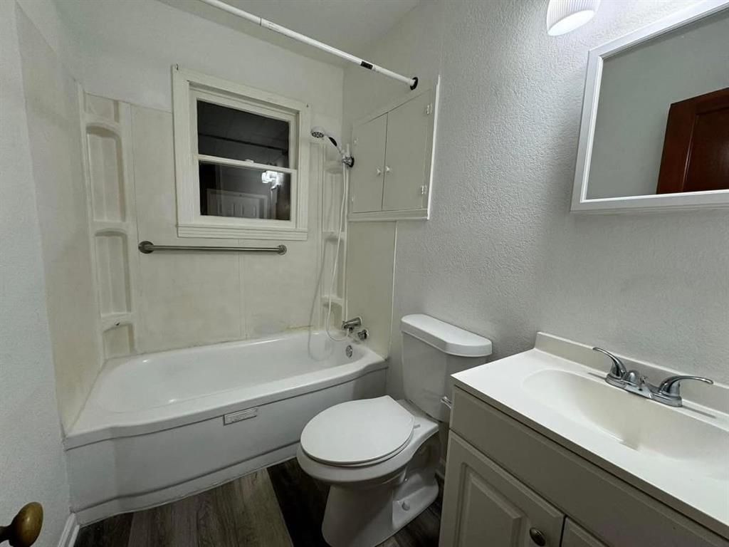 4393 Old Dallas Road Elm Mott, TX 76640 - Photo 15 of 19 Full bathroom with bathing tub / shower combination, wood finished floors, vanity, and a textured wall