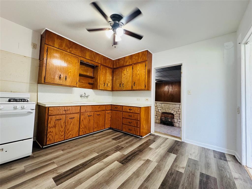 4393 Old Dallas Road Elm Mott, TX 76640 - Photo 8 of 19 Kitchen featuring white gas stove, brown cabinetry, ceiling fan, and light wood-type flooring