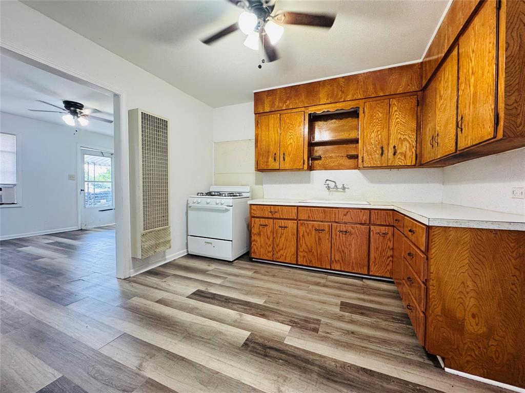 4393 Old Dallas Road Elm Mott, TX 76640 - Photo 9 of 19 Kitchen featuring white gas range oven, ceiling fan, a heating unit, and brown cabinets