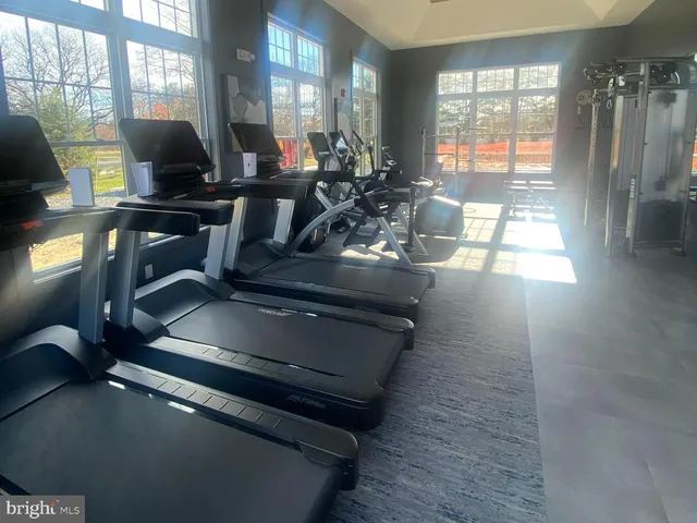 a living room with furniture gym equipment and large windows