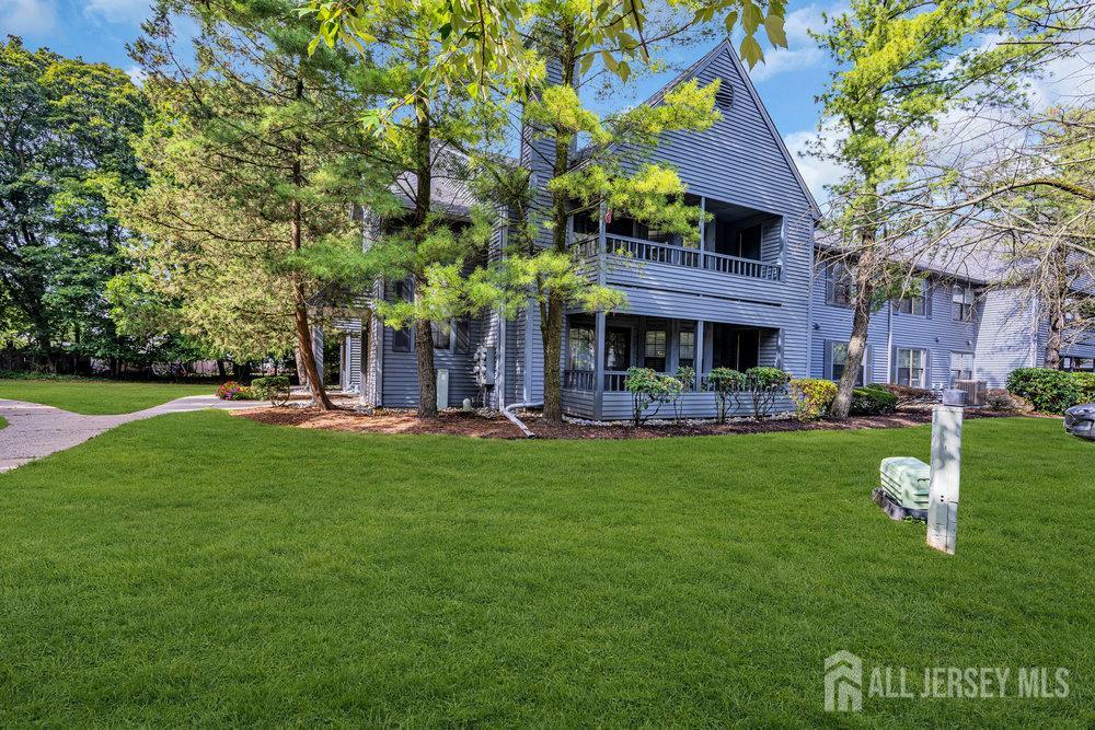 a view of a house with a big yard potted plants and large tree