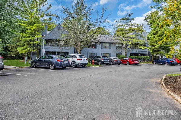 a view of road with card parked on side and retail shops