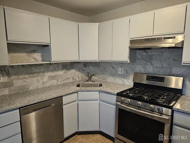 a kitchen with granite countertop cabinets stainless steel appliances and a sink