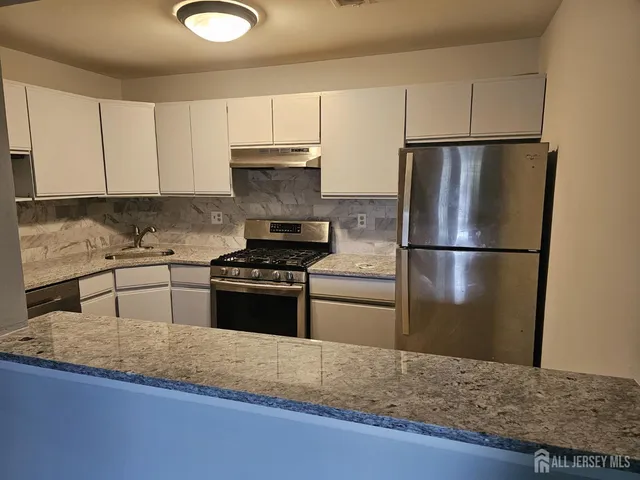 a kitchen with granite countertop a refrigerator stove and sink