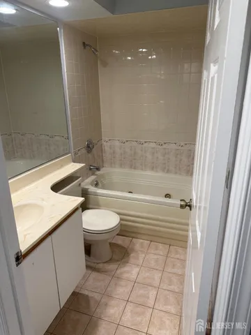 a bathroom with a granite countertop bathtub sink vanity mirror and toilet