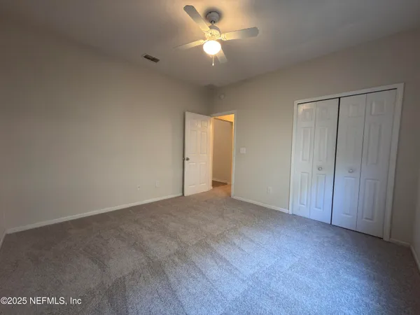 a view of an empty room and chandelier fan and fire place