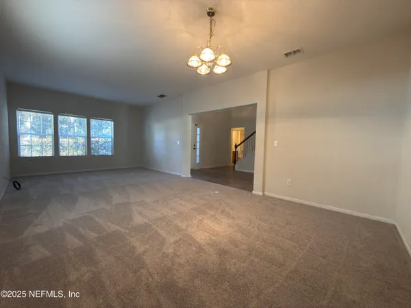 en empty room with windows and chandelier