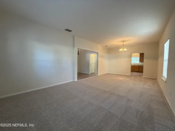 a view of a big room with windows and chandelier fan