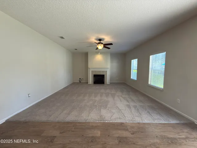 a view of an empty room and chandelier fan and fire place