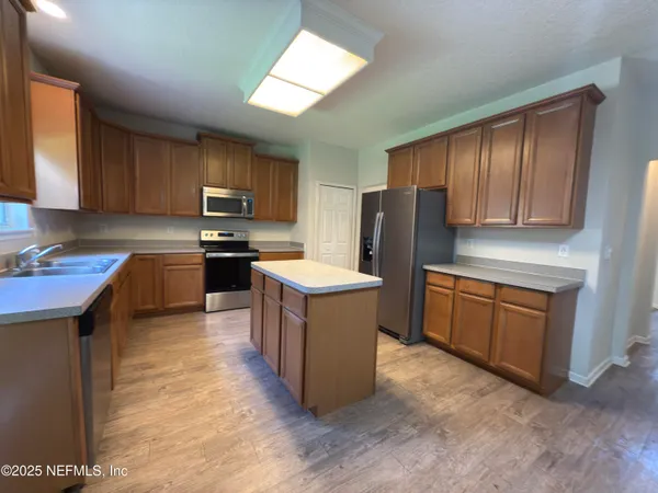 a kitchen with stainless steel appliances granite countertop a stove top oven a sink and a refrigerator