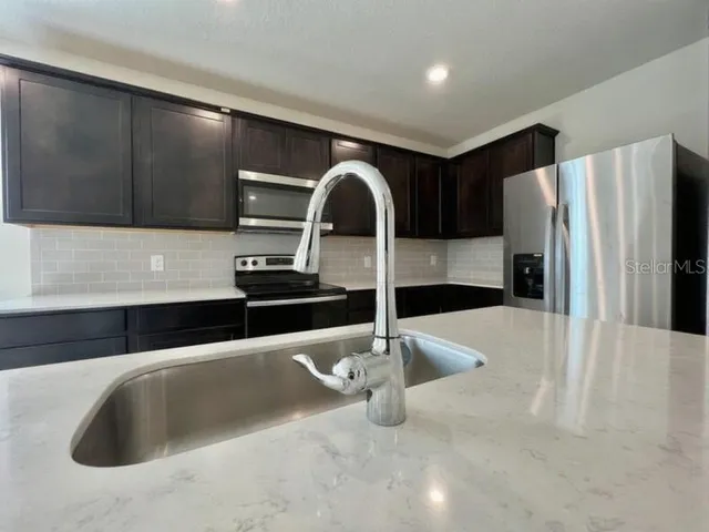 a kitchen with granite countertop a refrigerator and a sink