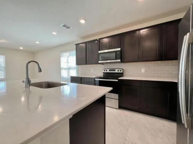 a kitchen with kitchen island a sink stainless steel appliances and cabinets