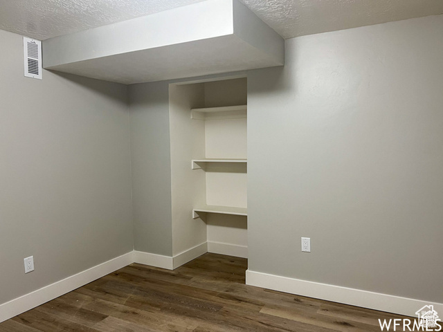 702 North 100 West Logan, UT 84321 - Photo 20 of 58 Finished basement featuring dark wood-style floors, baseboards, a textured ceiling, and visible vents