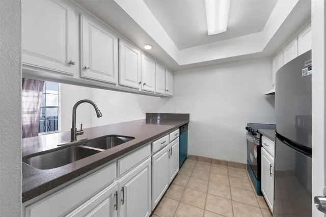 a kitchen with stainless steel appliances granite countertop a sink and a refrigerator