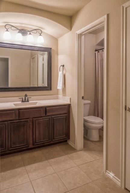 415 Harding Lane Lavon, TX 75166 - Photo 11 of 13 Bathroom vanity featuring a single basin, dark wood cabinetry, and a light-toned countertop