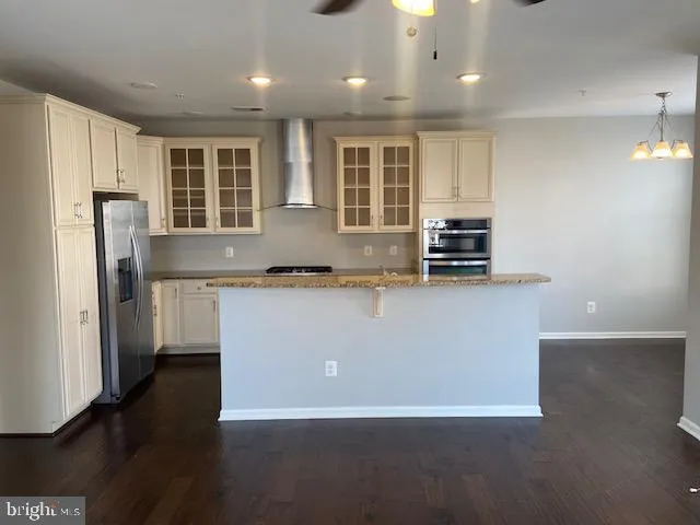 a view of kitchen with stainless steel appliances granite countertop a refrigerator a sink a stove and a refrigerator with wooden floor